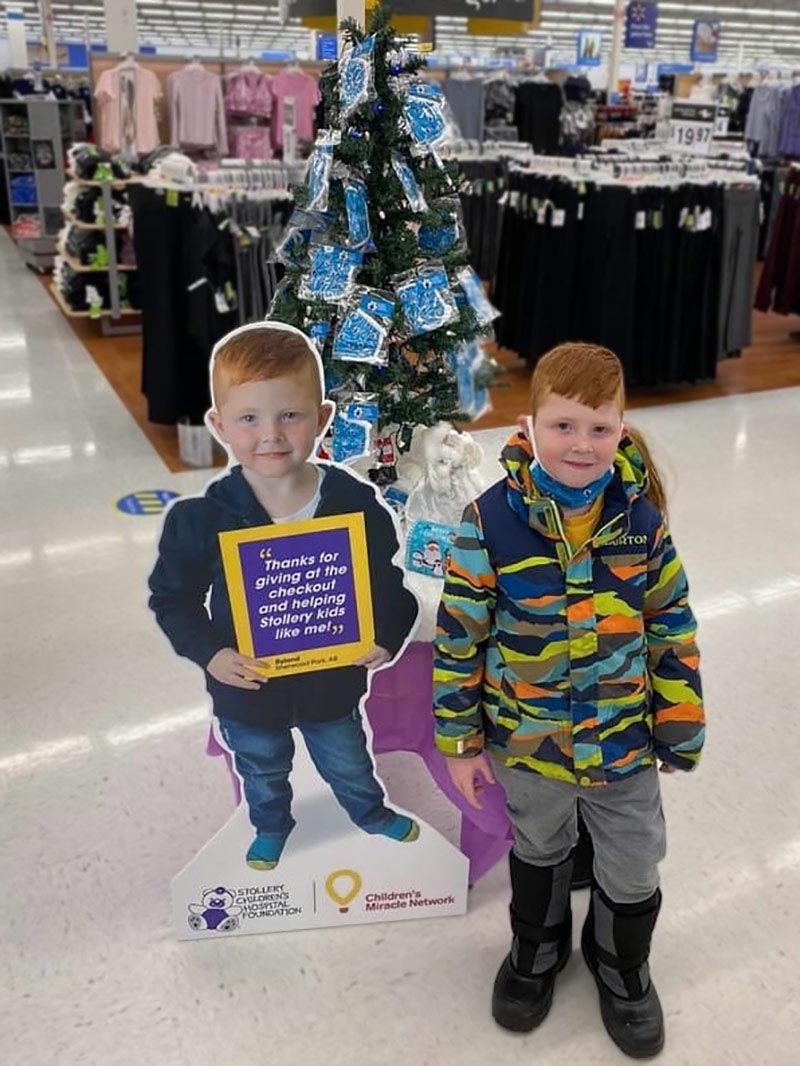 Little boy next to Stollery poster